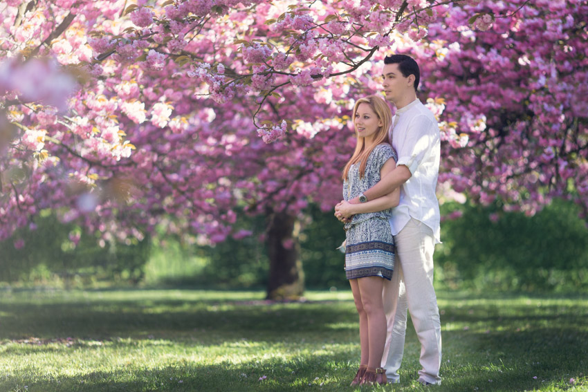 Séance engagement romantique dans un parc avec les cerisiers en fleurs.
